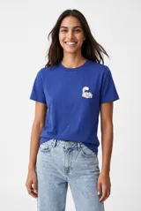 Remera azul de manga corta, con cuello redondo y pequeño estampado en el pecho del Gato de Cheshire de Alicia en el País de las Maravillas.