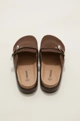 Suecos negros de estilo zueco con capellada de cuero sintético, detalle de hebilla metálica dorada y tachas decorativas alrededor de la suela. Poseen plantilla ergonómica y suela de plataforma dentada.