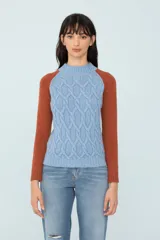 Sweater bicolor de tejido de punto, con mangas ranglán color ladrillo y cuerpo celeste con diseño de trenzas.