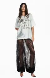 Camiseta de algodón en tono gris claro con efecto desgastado y lavado. Presenta un diseño gráfico frontal con la frase 'If it's meant to be then it will be' y una ilustración de un castillo, con detalles en pedrería o glitter. Posee un corte relajado y mangas cortas.