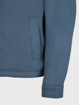 Campera azul con cierre de cremallera, cuello doblado, dos bolsillos inferiores a los lados, detalles distintivos de Tommy Hilfiger y logo de Tommy Hilfiger bordado en el pecho.