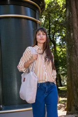 Bolso tipo tote confeccionado en corderito sintético color beige, con cierre principal y bolsillo interior. Presenta una etiqueta de cuero sintético en el frente.