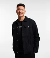 Campera de sarga negra, modelo trucker, con cuello camisero, recortes, dos bolsillos delanteros con solapa y abotonado total.