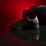 Championes Adidas modelo Superstar, color negro con las icónicas tres tiras laterales en acabado iridiscente y puntera de goma clásica.