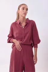 Camisa de cupro color lila de calce oversize, con cuello camisero y botones frontales a tono. Posee mangas largas con volumen y puños definidos.