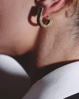 Pendientes dorados en forma de U con incrustaciones de pequeños cristales brillantes en toda la superficie.