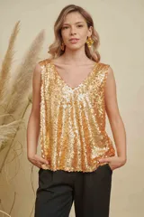 Musculosa de lentejuelas doradas con doble escote en V, tanto en el frente como en la espalda. Presenta breteles anchos y un corte levemente acampanado.