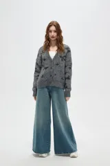 Cardigan de punto gris con estampado de estrellas negras, cuello en V, cierre frontal con botones y mangas largas con puños acanalados.