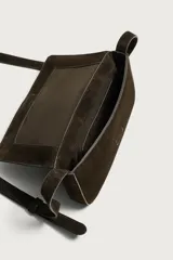Bolso tipo bandolera de piel con acabado serraje, compartimento principal con cierre de solapa e imán, bolsillo posterior y asa de hombro ajustable.