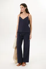 Musculosa azul marino de lino con escote en V, breteles de cuero marrón y pespuntes blancos decorativos.