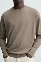 Jersey color crudo de tejido de punto, con cuello redondo y mangas largas. Corte amplio y terminaciones en rib.