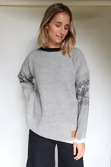 Buzo oversize de tejido de punto con diseño jacquard en mangas y espalda, cuello redondo y detalle de etiqueta de cuero sintético en el ruedo.