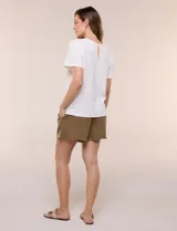 Blusa blanca de textura gofrada, de corte recto y semi holgado, con mangas cortas y escote redondo adornado con un canesú frontal en crochet calado.