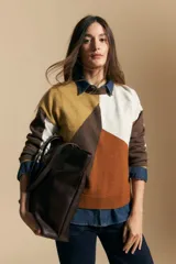 Sweater de tejido de punto con diseño geométrico de bloques de color en tonos tierra, marrón, ocre y blanco. Presenta cuello redondo, mangas largas y un corte relajado.