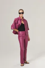 Pantalón de cuero rosa chicle, de corte recto, tiro medio, cierre lateral plateado y tajos en el dobladillo.