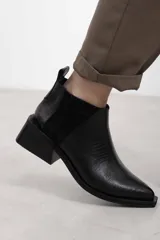 Botineta de cuero negro con textura sutil, con elásticos laterales y taco cuadrado bajo.