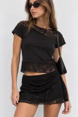 Short de tul negro con diseño de encaje semitransparente, corte cruzado y superpuesto con ruches en los laterales.