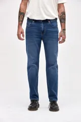 Jean de corte slim, color azul medio, con diseño clásico de cinco bolsillos, cierre frontal con botón y cremallera.