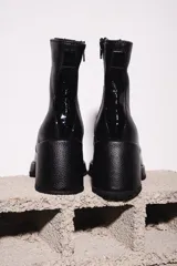 Botinetas negras de cuero con caña baja, punta cuadrada y cierre lateral con cremallera.