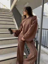 Buzo oversize de algodón color marrón, con diseño de costuras expuestas en contraste y terminaciones desflecadas en mangas y ruedo.