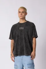Remera negra con efecto acid wash, corte oversize y pequeño estampado de texto en el pecho.