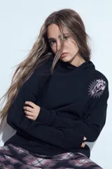 Canguro negro de silueta relajada con capucha integrada. Presenta un estampado gráfico de un corazón anatómico en color rosado en el pecho.