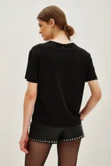 Remera negra de manga corta con cuello redondo, decorada con pequeñas aplicaciones brillantes dispersas en la parte frontal y mangas.