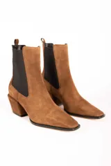 Bota tipo Chelsea de gamuza color marrón, con paneles laterales elásticos en color negro, puntera cuadrada y taco cuadrado de altura media.