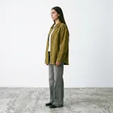 Camisa de estilo sobrecamisa en color mostaza, confeccionada en tejido de algodón con acabado desgastado en los bordes y costuras. Presenta cierre frontal con botones, bolsillos en el pecho y mangas largas con puños abotonados.