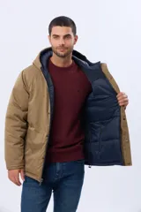 Campera reversible para hombre, con un lado liso en color tostado y el otro acolchado en color azul marino. Cuenta con capucha integrada, cierre frontal y bolsillos funcionales.