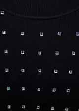 Vestido corto de punto fino en color negro, con diseño entallado, cuello perkins y manga larga. Presenta un estampado de strass brillante distribuido por toda la prenda.