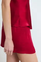 Conjunto de pijama de satén rojo, compuesto por un top de breteles finos con detalle de puntilla en el escote y un short con cintura elastizada y lazo ajustable.