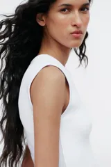 Top blanco de manga sisa con cuello redondo y corte ajustado al cuerpo.