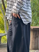 Remerón de manga larga, color blanco con rayas horizontales negras, corte oversize con tajos laterales y bajo redondeado.