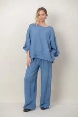 Blusa de lino color celeste, con cuello redondo, mangas amplias tres cuartos con volados en los puños y detalle de alforzas horizontales en el ruedo.
