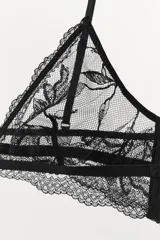 Sujetador triangular negro de encaje con bordados florales, escote pico, tirantes finos ajustables y cierre de ganchos en la espalda.