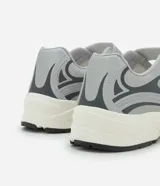 Championes de estilo híbrido entre jogging y Mary Jane, confeccionados en poliuretano. Presentan un diseño con cierre de tira adherente en el empeine, suela robusta y detalles en tonos grises y plateados.