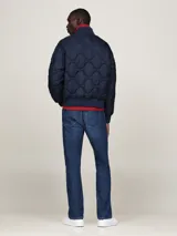 Campera bomber azul marino con diseño acolchado, cuello estilo béisbol, cierre de cremallera, dos bolsillos delanteros ribeteados, cuello, puños y bajo de punto canalé y parche con el logo de Tommy Hilfiger en la manga.