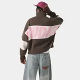 Buzo tejido de punto con cierre frontal completo, cuello polo y diseño de bloques de color en marrón, blanco y rosa. Presenta el logo de la marca tejido en jacquard en el frente, con corte oversize y largo cropped.