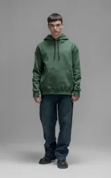 Hoodie oversize color verde, confeccionado en frisa premium con textura gamuzada. Presenta capucha ajustable con cordones personalizados, bolsillo frontal tipo canguro y puños con abertura para pulgar.