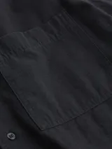 Camisa Calvin Klein de manga corta, confeccionada en algodón texturizado, con cuello tipo cubano, cierre frontal de botones y bolsillo de parche en el pecho con etiqueta de la marca.