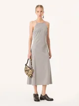 Vestido largo de punto gris con brillo, corte al cuerpo en la parte superior con breteles finos y espalda tipo halter, y falda evasé.