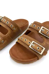 Sandalias de cuero color tostado, con doble tira sobre el empeine, ojales metálicos y hebillas plateadas ajustables.