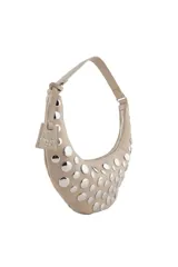 Cartera tipo hobo de Las Oreiro en color beige, con diseño de media luna y decorada con tachas metálicas plateadas en toda su superficie frontal. Incluye una correa fija y un dije colgante con el logo de la marca.