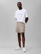 Short de jogging color beige, de tejido de punto de algodón acanalado, con cintura elástica, bolsillos laterales y trasero. Presenta logo CK bordado en blanco en la pierna izquierda.
