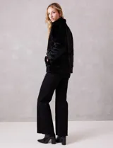 Chaqueta de piel sintética de alta densidad, con silueta recta, cuello alto envolvente y cierre frontal oculto. Cuenta con bolsillos laterales y forro interno a tono.