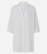 Salida de playa tipo túnica camisera blanca, con mangas 3/4, cuello camisero y cierre frontal con botones. Confeccionada en algodón certificado BCI.