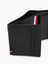 Billetera trifold de cuero vacuno color negro con textura acanalada y logo de Tommy Hilfiger en la parte inferior. Cuenta con múltiples ranuras para tarjetas, compartimento para billetes y bolsillo interior con cierre a presión para monedas.
