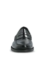 Mocasines tipo slip-on de cuero negro con acabado brillante, diseño clásico con banda frontal y suela de poliuretano con tecnología Bounce para mayor confort y absorción de impactos.