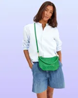 Bandolera verde de cuero tejido con correa de hombro ajustable y cierre de cremallera.